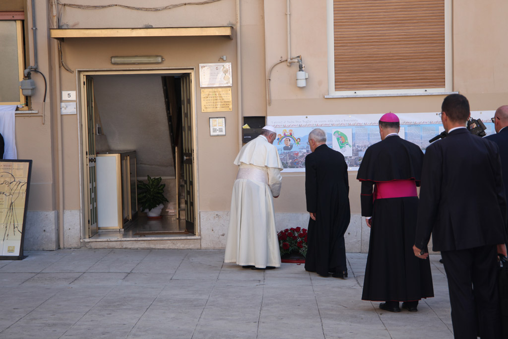 Papa Francesco depone una corona di rose sul medaglione di bronzo installato nel punto in cui fu trovato morente il Beato Puglisi